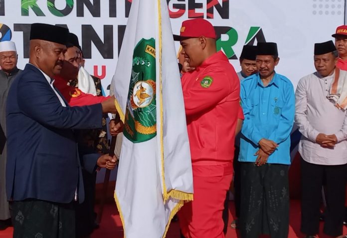 Bupati Kukar Edi Damansyah (kiri), saat menyerahkan Bendera Pataka Kukar ke Ketua KONI Kukar, Rahman saat pelepasan Kontingen Kukar untuk Porprov VII Kaltim. (Ady/Radar Kukar)