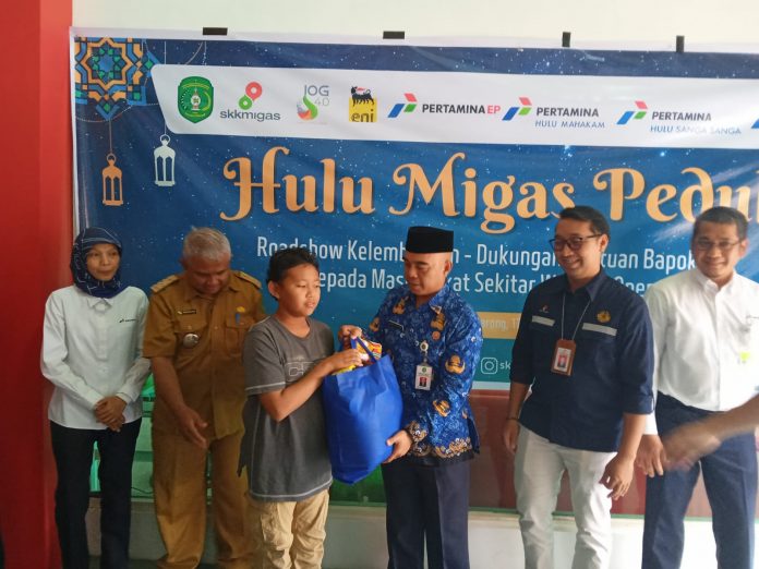 Asisten I Setkab Kukar, Ahmad Taufik Hidayat (baju biru), saat menyalurkan sembako bantuan dari SKK Migas, pada anak yatim. (Ady/Radar Kukar)
