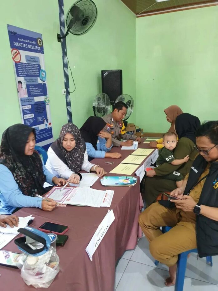Bhabinkamtibmas Tani Bhakti saat dampingi petugas posyandu rutin balita di Desa Tani Bhakti. (Istimewa)